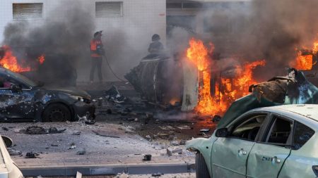 People try to extinguish fire on cars following a rocket attack from the Gaza Strip in Ashkelon, southern Israel, on October 7, 2023. (Photo by AHMAD GHARABLI / AFP)
