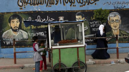 Palestinian children purchase food from a street vendor next to a Hamas police station adorned with paintings of abducted Israeli solider, Gilad Shalit, and air force pilot, Ron Arad on March 29, 2010 in Jabaliya, Gaza Strip. (Photo by Warrick Page/Getty Images)