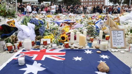Australia's flag is seen next to floral tributes outside Bondi Pavilion in Sydney on December 16, 2025, in honour of victims of the Bondi Beach shooting. Australia's leaders have agreed to toughen gun laws after attackers killed 15 people at a Jewish festival on Bondi Beach, the worst mass shooting in decades decried as antisemitic "terrorism" by authorities.